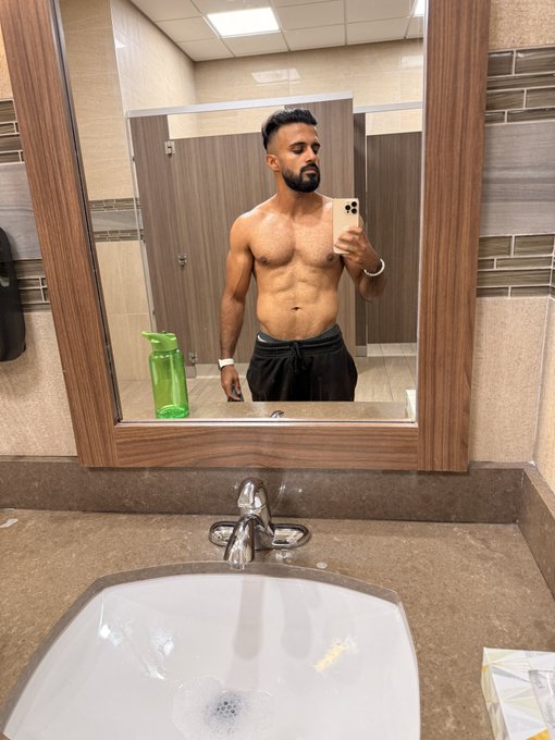 A shirtless man takes a gym mirror selfie in a public restroom, showing off his muscular physique while holding up his phone. The caption celebrates his 85lb incline press strength at 140lbs bodyweight, with the photo visually reinforcing his claim of pound-for-pound strength gains.