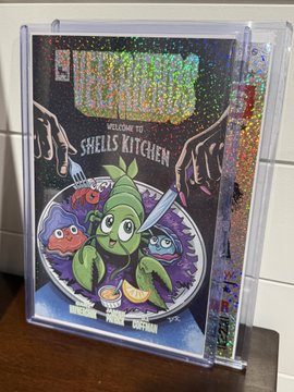 A holographic foil cover of the indie comic "Shells Kitchen" #1, subtitled "Welcome to Shells Kitchen," is encased in a clear plastic sleeve and features cartoon vegetable characters.