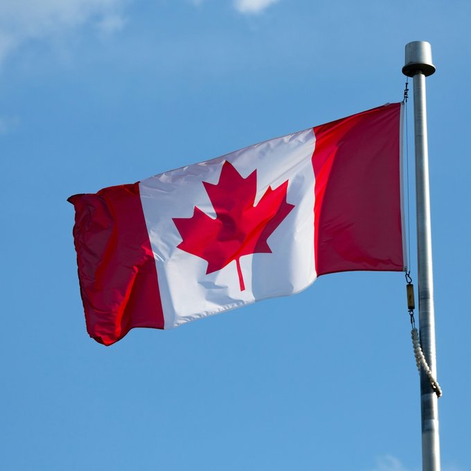 The Canadian flag waves against a clear blue sky, representing Canada where the OSFI has clarified its neutral stance on tokenized deposits. The flag symbolizes the regulatory body issuing this guidance on technology-neutral financial products.
