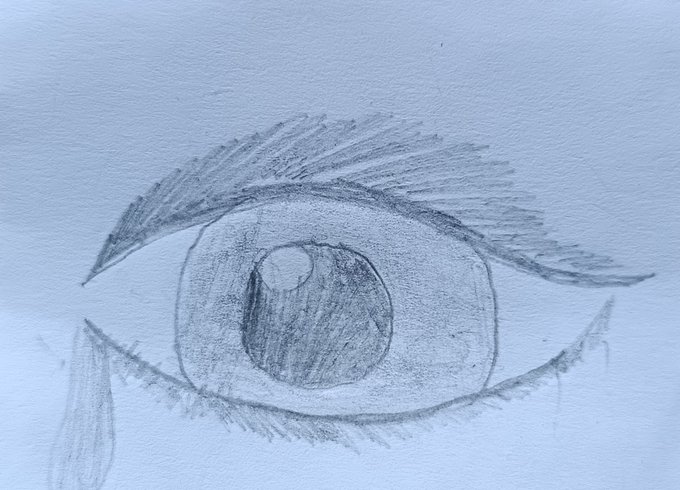 A pencil sketch on paper depicting a detailed drawing of a human eye with shading and eyelashes.