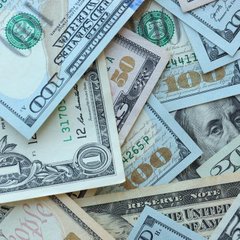A scattered pile of various U.S. dollar bills including $50 and $100 denominations, showing the faces and details of the currency.