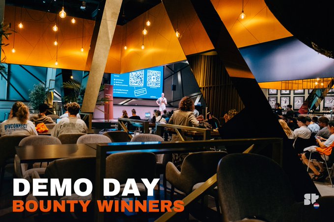 Event photo captioned 'DEMO DAY BOUNTY WINNERS' showing an audience watching a presentation at what appears to be a conference venue.