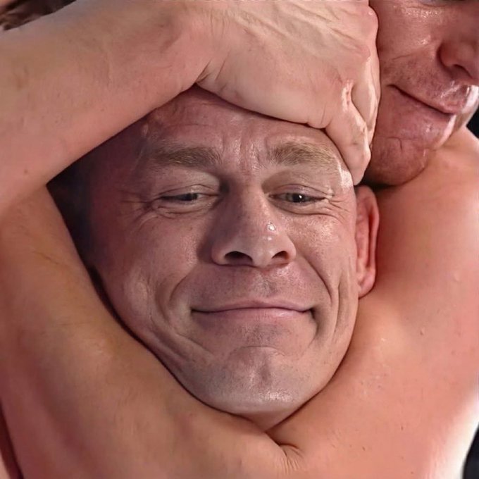 A close-up of a man's face with a calm, smug smile as he is being squeezed tightly from behind by another person's arms, his cheeks and nose red from the pressure. The image humorously illustrates the meme's message—a crypto holder remaining composed and unbothered even while being "squeezed" by someone trying to hurt him.