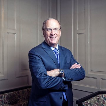A professional portrait shows a smiling older man in a blue suit with glasses, standing confidently with arms crossed against a paneled wall. The image likely represents a BlackRock executive, connecting to the post about Blackrock's continued institutional Bitcoin purchases totaling $128.33M.