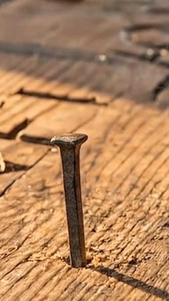 The image features a close-up view of a nail sticking out from a piece of wood, with the background blurred. The text "The town has been quiet... Too quiet. Something is being prepared ...." appears to be written on this wooden surface. This scene could potentially be related to Bitcoin or other cryptocurrencies, as it seems like there might be some sort of digital transaction taking place in the image.