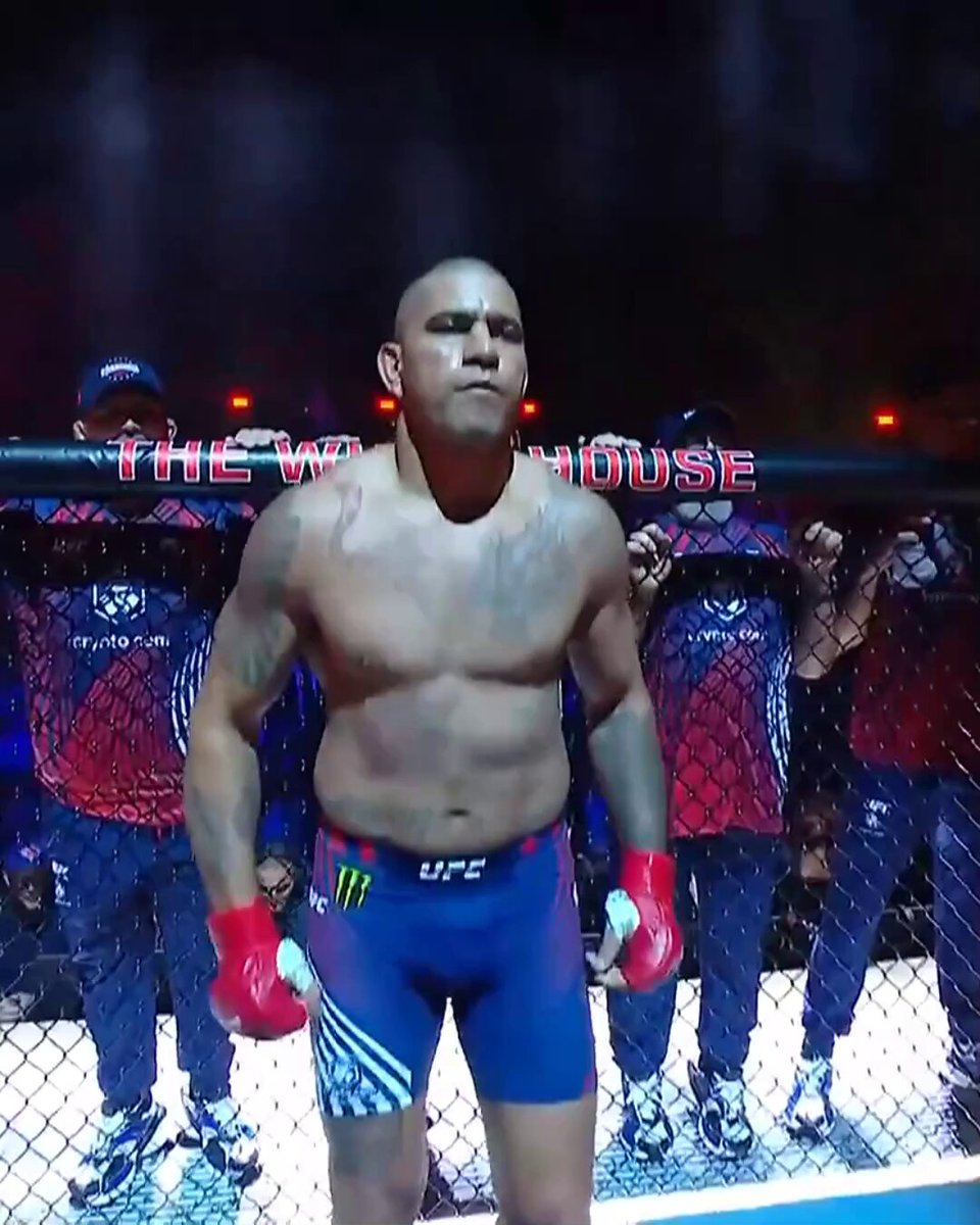 The image features a man standing in front of a fence, wearing shorts and boxing gloves. He appears to be posing for a photo or participating in an event related to the UFC. The background shows other people present as well, suggesting that this is likely a public event or gathering. The post about the fighter being at the UFC White House seems to be promoting a specific fighter or highlighting his participation in a particular event.