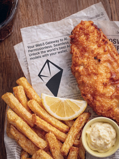 A close-up photograph of fish and chips served on newspaper-print paper, featuring a piece of breaded fried fish, thick-cut fries, a lemon wedge, and a small cup of tartar sauce.