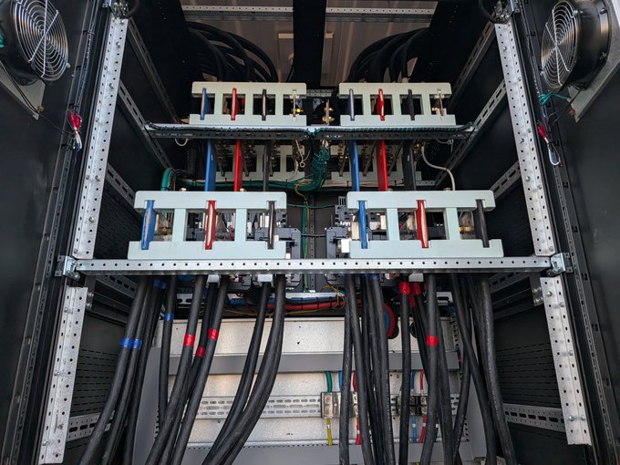 A server rack interior showing heavy power infrastructure with large industrial bus bars, cooling fans, and thick cables.