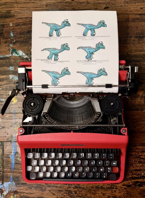 A vintage red typewriter sitting on a distressed wooden surface with a sheet of paper feeding through it, displaying a pattern of illustrated blue dinosaurs.