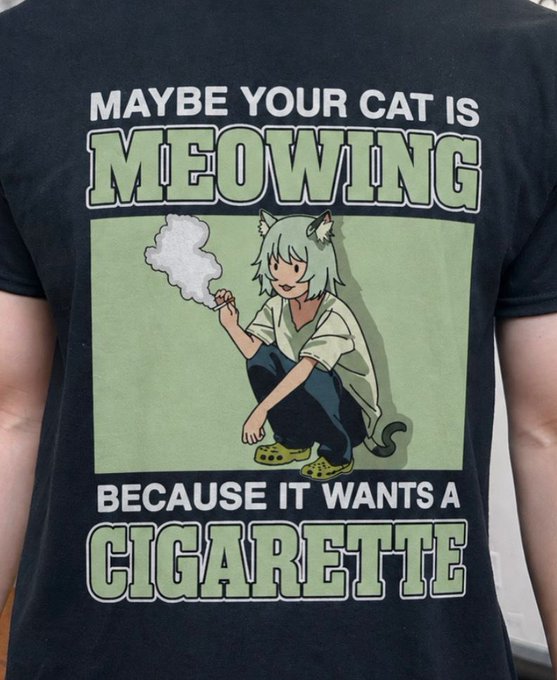 A person wearing a black t-shirt featuring anime-style art of a cat character smoking, with the text 'MAYBE YOUR CAT IS MEOWING BECAUSE IT WANTS A CIGARETTE.'