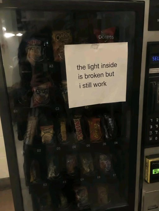 A vending machine displays a handwritten note reading "the light inside is broken but i still work," relating to the post's sentiment of relating to and sympathizing with the resilient machine despite its broken light. Various snacks including Doritos and Cheetos are visible behind the dim glass.