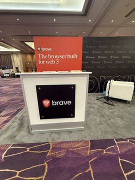 A white event stand branded with 'brave' features a red screen displaying the text 'The browser built for web3'.