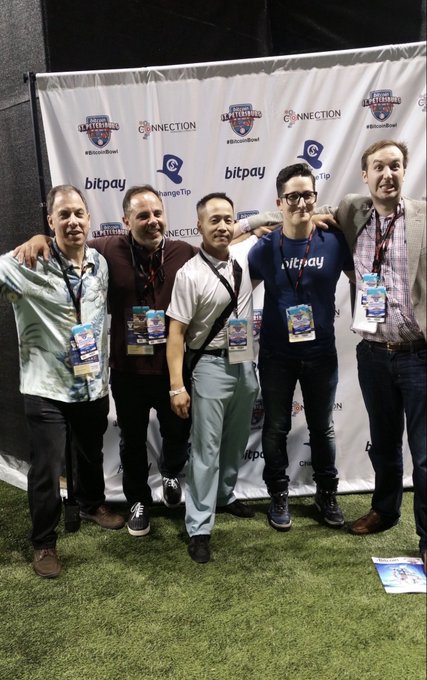Five men pose together at what appears to be a Bitcoin Conference, standing in front of a backdrop featuring logos for 'BITCOIN CONFERENCE NASHVILLE', 'bitpay', and 'CONNECTION'.