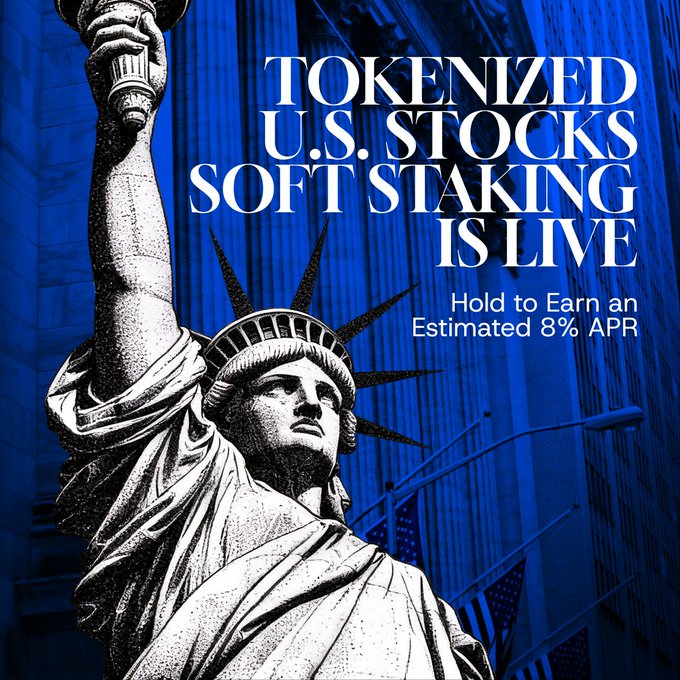A stylized graphic featuring the Statue of Liberty overlaid on a deep blue skyscraper backdrop, with bold white text reading "TOKENIZED U.S. STOCKS SOFT STAKING IS LIVE — Hold to Earn an Estimated 8% APR." The promotional visual reinforces the post's announcement of soft staking rewards on tokenized U.S. stock tickers including BLKHION, BLKDIGON, MAG7XON, BRAINON, YLD5ON, YLD8ON, and BLKGRWON.