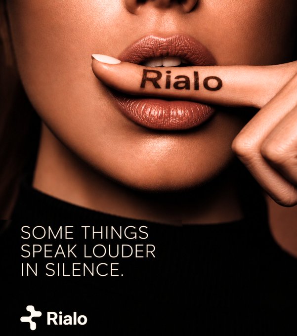 An advertisement for 'Rialo' featuring a close-up of a woman's lips with the word 'Rialo' written on her finger held to her mouth, with the tagline 'SOME THINGS SPEAK LOUDER IN SILENCE.'