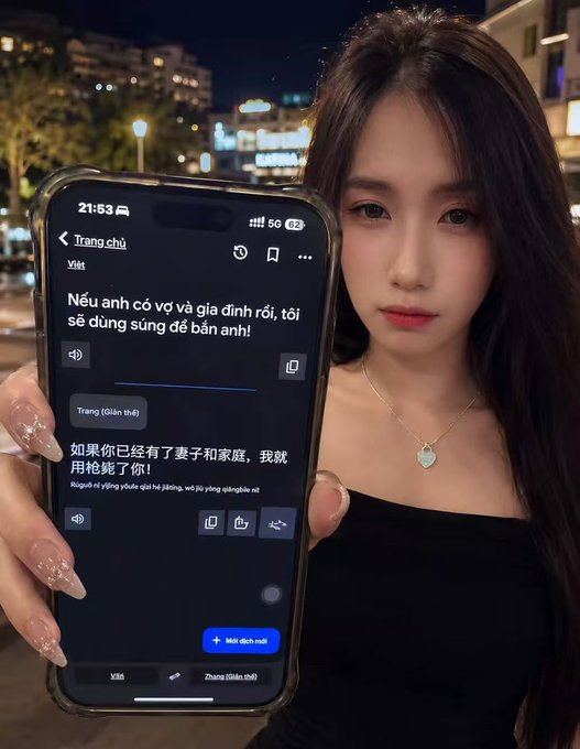 A young woman in a black top holds up her phone displaying a Vietnamese-Chinese translation app with the text "Nếu anh có vợ và gia đình rồi, tôi sẽ dùng súng để bắn anh!" (Chinese: "如果你已经有了妻子和家庭，我就用枪毙了你!") which translates to a dramatic threat about shooting someone if they have a wife and family. The caption's melancholic theme of love and emotional turmoil fits the image's dramatic, love-obsessed declaration on the translation screen.