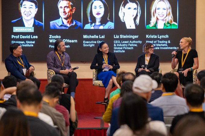 A panel discussion at a conference with five speakers seated on stage, identified on the large screen behind them as Prof David Lee (Chairman, Global Fintech Institute), Zooko Wilcox O'Hearn (Founder, Zcash), Michelle Lai (Executive Chair, Sovryn), Liz Steininger (CEO, Least Authority), and Krista Lynch (Head of Trading).