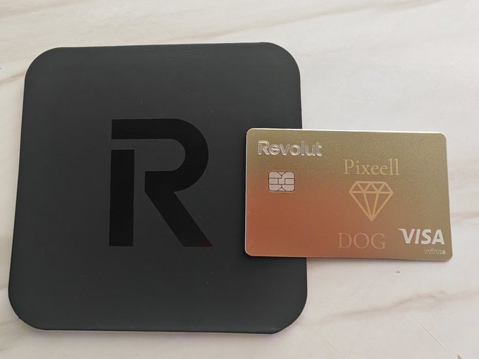 The image features a black square credit card with the word "Revolut" written on it, as well as a gold-colored diamond-shaped Visa card placed next to it. The text on both cards reads "Revolut PIXEL VISA DOG". This suggests that someone has recently received these cards and is now listing them in a post about Bitcoin.