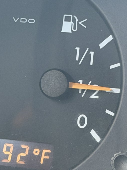 A vehicle's fuel gauge indicates the tank is exactly half full, with a digital display below reading "92°F".