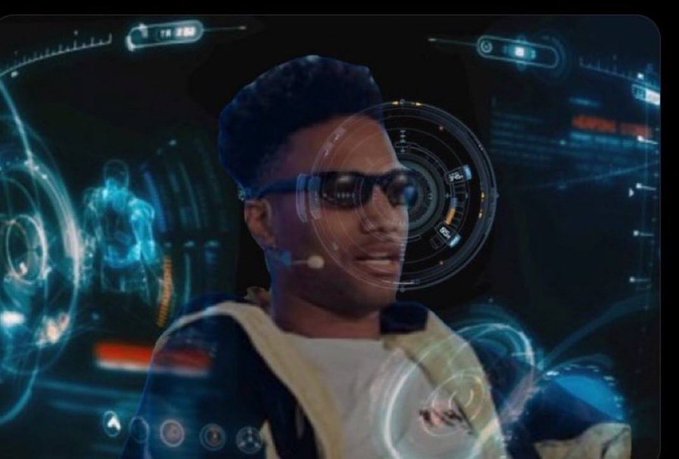 A scene showing a young man with styled hair and dark sunglasses in front of a futuristic, holographic HUD/interface display featuring glowing blue circles, data panels, and a humanoid figure, giving a sci-fi or AR effect.
