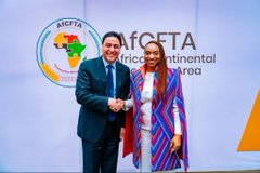 Two people shake hands in front of an AfCFTA (African Continental Free Trade Area) and AFCFTA banner at what appears to be a formal event.