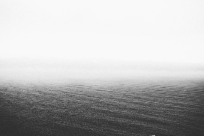 A misty, monochrome seascape where fog blurs the horizon line between sea and sky, evoking the patience, solitude, and disciplined clarity required for high-quality trading as described in the post.