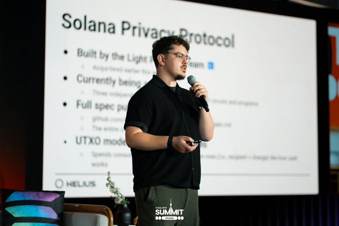 A man giving a presentation while holding a microphone, standing in front of a slide titled 'Solana Privacy Protocol' listing bullet points like 'Built by the Light' and 'Full spec pub', with a 'HELIUS' logo and 'SUMMIT' sign visible.