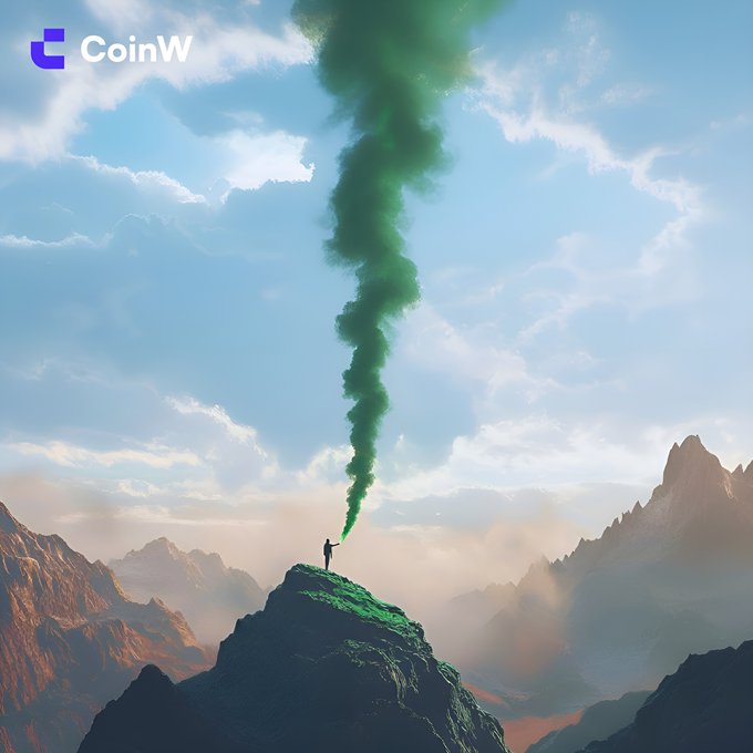 A CoinW promotional image showing a person standing on a mountain peak releasing a large plume of green smoke into a cloudy sky.