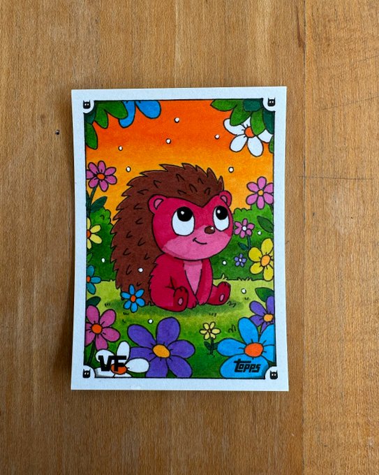 The image features a cartoon drawing of a cute little hedgehog sitting on top of flowers, surrounded by an array of colorful flowers. The hedgehog appears to be looking at something or someone, possibly another hedgehog or a human viewer. The background is filled with various types and colors of flowers, creating a vibrant and lively atmosphere.