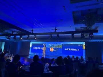 A keynote presentation takes place at a Gate event, featuring a speaker on stage with a large screen displaying "KEYNOTE" and "从交易到生活" (From Trading to Life) text, while attendees are seated at tables in the dimly lit blue venue. The image directly relates to the post's mention of a Gate event and showcases the formal presentation setting the user attended thanks to Godus Gate's invitation.