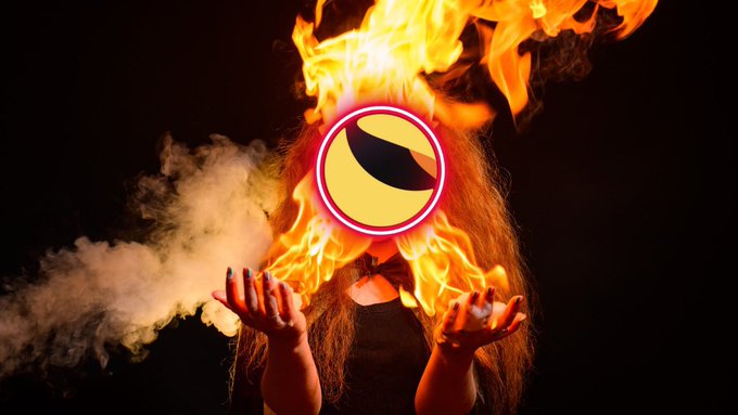 The image shows a woman with long hair whose face is obscured by a flaming circular logo (resembling Terra Classic's branding), holding out her hands as fire and smoke billow from them—visually symbolizing the burning and destruction of $LUNC and $USTC tokens referenced in the caption. The dramatic flames serve as a literal depiction of the token burn mechanism fueling Terra Classic's deflationary efforts.