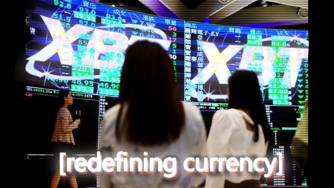 A stock market display with digital overlays of currency symbols and the text '[redefining currency]', showing people viewing exchange rate screens.