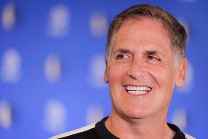 A smiling man, identified by the accompanying post as billionaire entrepreneur Mark Cuban, appears against a blue branded backdrop as he shares his bullish take that AI chips are emerging as a new asset class akin to crypto. His optimistic expression mirrors his forward-looking investment commentary on GPUs and AI accelerators becoming the next major investment frontier.