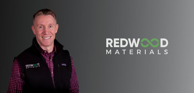 A man wearing a black Redwood Materials vest over a checkered shirt standing against a dark background, with the 'REDWOOD MATERIALS' logo displayed on the right.