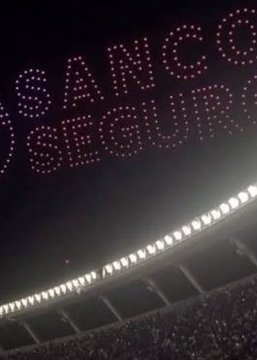 A nighttime stadium scene shows a crowd below as drones spell out "SANCO SEGURO" (part of "Sancor Seguros") in red lights in the sky, referencing the insurance company's controversial drone show advertisement that aired during Messi's farewell match.