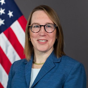 SEC Commissioner Hester Peirce, wearing glasses and a blue blazer, poses for an official portrait with an American flag in the background, following her statement supporting the agency's proposed crypto fundraising framework.