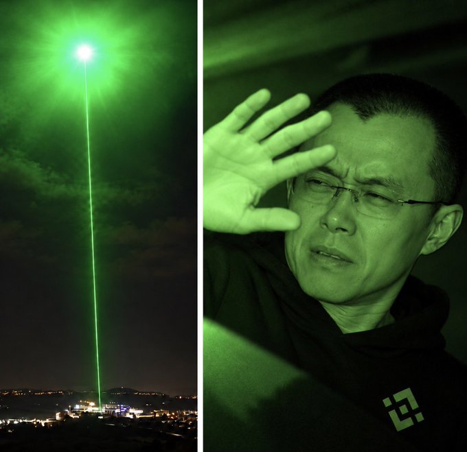 A split image shows a piercing green laser beam shooting into the night sky on the left, while on the right a man shields his eyes from its bright glow, visually reinforcing the post's ominous message that "$BTC" is on its way. The dramatic green lighting ties directly to the iconic green associated with Bitcoin and cryptocurrency markets.