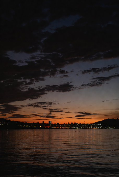 The image shows a beautiful sunset over water with a city skyline in the background. There are two projects worth watching at this time of day - @useTria and Tria. The post suggests that these projects offer cashback rewards for users who make purchases on their platforms, which is an interesting feature to consider when deciding what to watch during this serene evening.