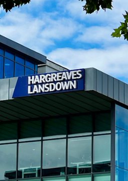 An exterior view of a building shows a blue 'HARGREAVES LANSDOWN' sign against a cloudy sky.