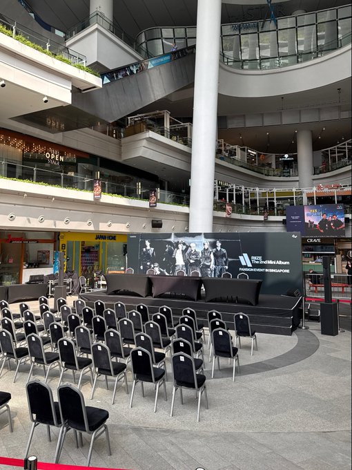 Inside a multi-level shopping mall, rows of chairs face a raised black stage promoting BLACKPINK Jennie’s “Ruby” album and fan event in Singapore. The “HOT” post likely teases the anticipated mall event or livestream setup.