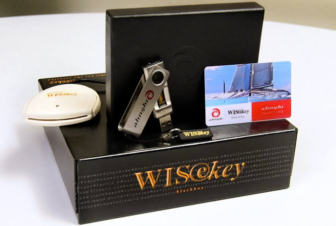 A promotional display shows a WISeKey product set, including a USB drive, an NFC token, a round token, a keychain, and a "WISeSat" satellite card, arranged around a black box.
