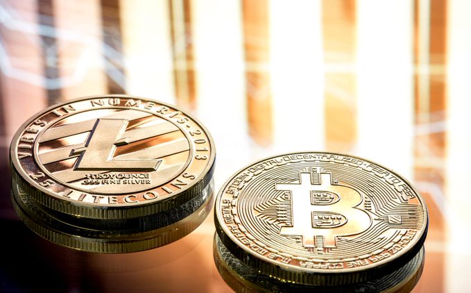 Two physical gold-plated commemorative coins—one displaying the Litecoin "L" logo with text reading "VIRES IN NUMERIS 2013, 1 TROY OUNCE .999 FINE SILVER" and "LITECOINS," and the other showing the Bitcoin "₿" symbol inscribed with "BITCOIN DIGITAL DECENTRALIZED PEER TO PEER"—rest on a reflective surface, visually reinforcing the post's endorsement of $BTC and $LTC as reliable, established alternatives to volatile memecoins.