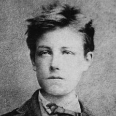 A vintage black-and-white portrait photograph of a young man with messy hair, wearing a suit jacket, white shirt, and dark tie.