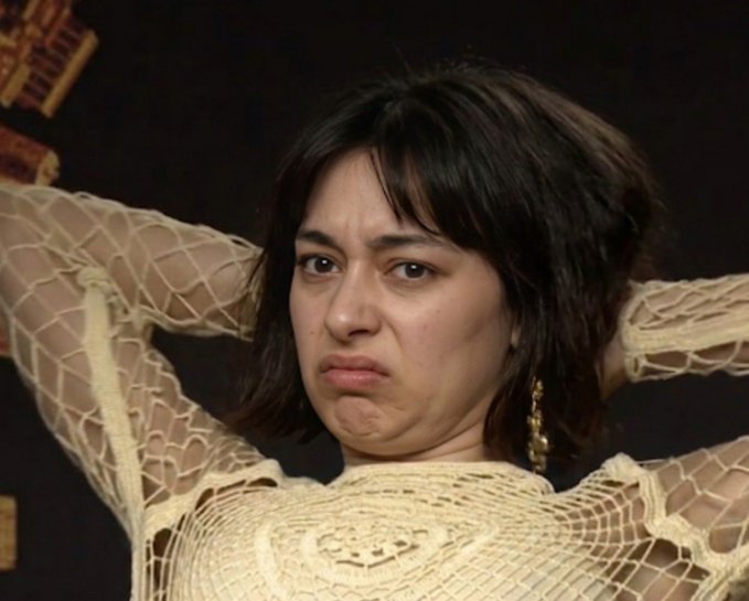 A woman with a pained, scrunched facial expression holds her hands behind her head while wearing a crocheted top. Her exaggerated grimace of regret or disappointment visually echoes the post's warning about traders who flock to low-priced NFTs without genuine appreciation for the art, mocking their superficial "collector" facade.