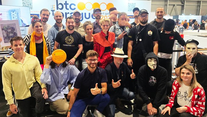 The image features a group of people posing for a photo at an art gallery, with the name "Avalatara" prominently displayed. The group consists of both men and women, all dressed up and smiling for the camera. They are gathered around a table that has a frisbee on it, suggesting they might be attending an event or gathering related to Bitcoin or cryptocurrency. The post also mentions that the artwork is sold at "Timeshifting Prague", which could indicate that this particular art piece holds some significance or value in the context of Bitcoin and cryptocurrency discussions.
