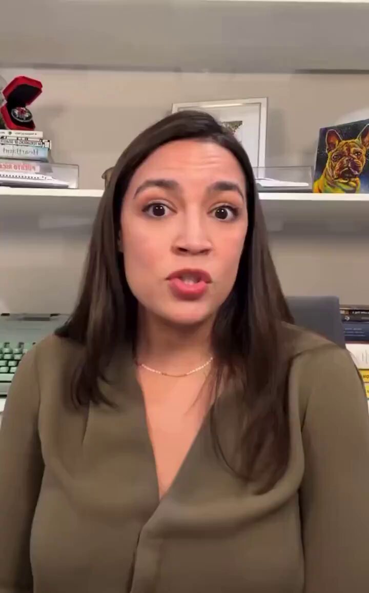The image features a woman with long brown hair wearing a green blouse, standing against a gray wall. She appears to be making a face or showing an expression of surprise while looking at the camera. The caption below her reads "“Trillionaire” @elonmusk". This suggests that she might be discussing or reacting to something related to Elon Musk's personal life or business, as indicated by the image and its caption.