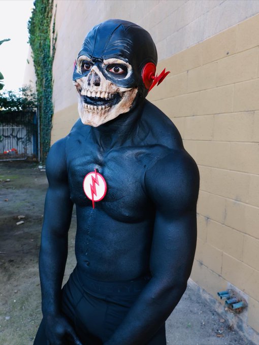 A muscular figure in a black suit with a skull mask and a red lightning bolt emblem on the chest stands against a brick wall, embodying the post's frustration about missing out on a project "mooning" in value and wanting to "crash tf out."