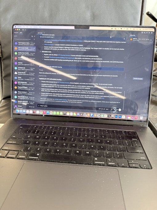 A MacBook laptop on a couch displaying a chat interface (appearing to be with "Geometric Consulting") showing instructions for submitting research ideas to the NYU CGAAC Incubator.