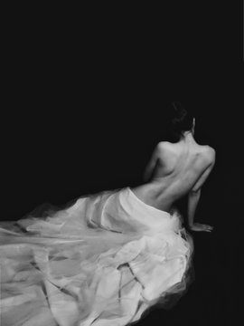 A black and white self-portrait of a woman seen from behind, draped in flowing white fabric against a dark background, illustrating the artistic "Trace of light" series being sold at 617 Gallery. The ethereal, luminous quality of the subject visually embodies the emotional warmth and gratitude expressed in the caption for the gallery's support.