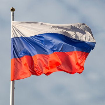The Russian flag waves against a cloudy sky, symbolizing the country's regulated crypto market launch on September 1, which is projected to reach $46 billion in trading volume during its first year.